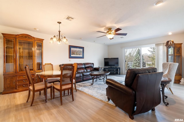 living room with ceiling fan with notable chandelier and light hardwood / wood-style flooring