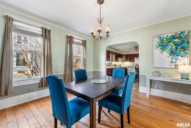 dining area featuring crown molding, a notable chandelier, and light hardwood / wood-style flooring