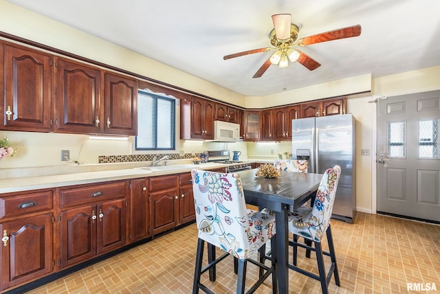 kitchen with sink, a kitchen breakfast bar, ceiling fan, and appliances with stainless steel finishes