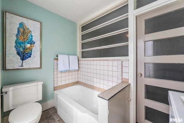 bathroom featuring toilet and a tub to relax in