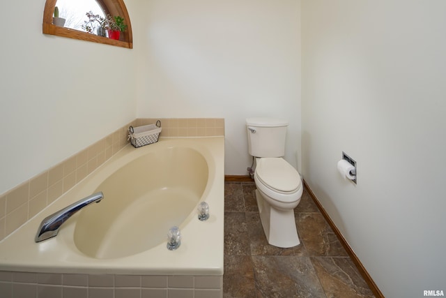 bathroom with toilet and tiled tub