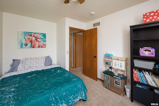 carpeted bedroom featuring ceiling fan and a textured ceiling