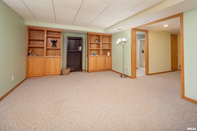 unfurnished living room with a drop ceiling, light colored carpet, and a chandelier