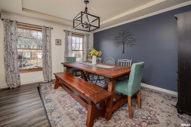 dining room featuring a chandelier, a textured ceiling, ornamental molding, dark hardwood / wood-style floors, and a raised ceiling