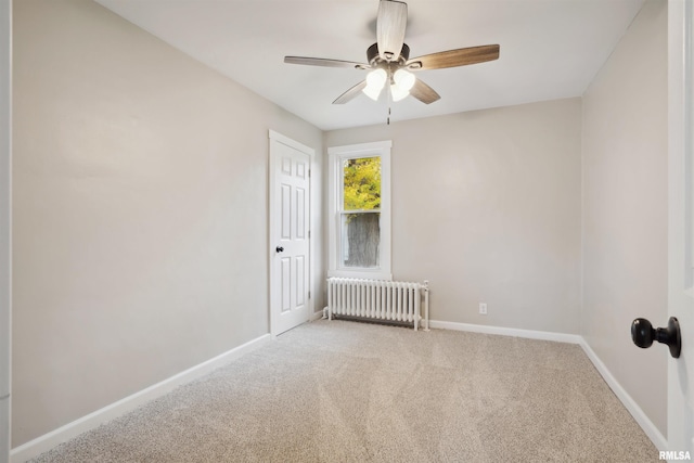 carpeted empty room featuring radiator heating unit and ceiling fan