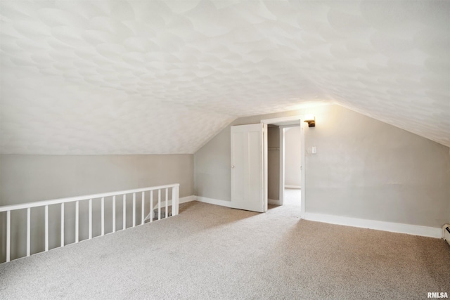 additional living space featuring vaulted ceiling, carpet floors, and a textured ceiling