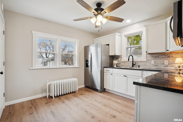 kitchen with white cabinetry, appliances with stainless steel finishes, radiator, and sink