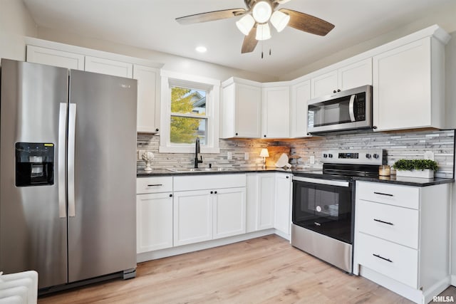 kitchen featuring sink, tasteful backsplash, light hardwood / wood-style flooring, stainless steel appliances, and white cabinets