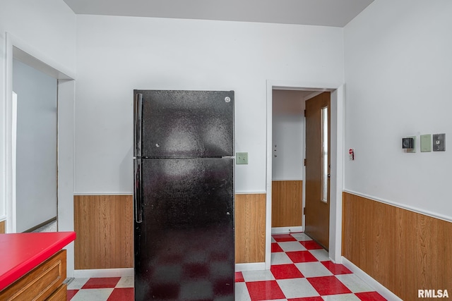 kitchen with black refrigerator and wooden walls