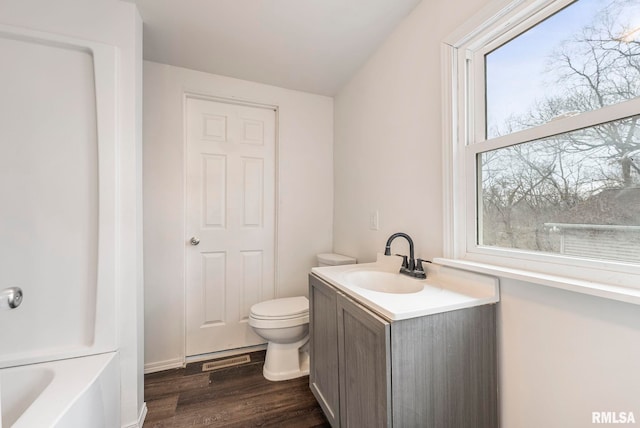 full bathroom featuring a tub to relax in, visible vents, toilet, vanity, and wood finished floors