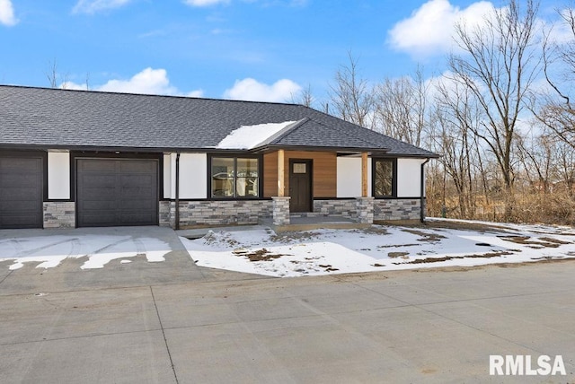 view of front of house featuring an attached garage, stone siding, driveway, and roof with shingles