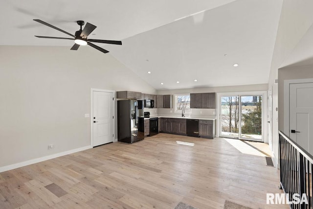 kitchen with black appliances, light wood-style flooring, light countertops, and a sink