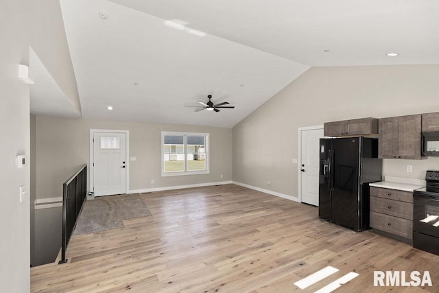 kitchen featuring light wood finished floors, lofted ceiling, light countertops, open floor plan, and black appliances