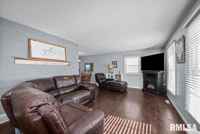 living room featuring wooden walls, a textured ceiling, and dark hardwood / wood-style flooring