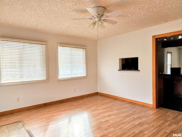 unfurnished room with ceiling fan, light hardwood / wood-style flooring, and a textured ceiling