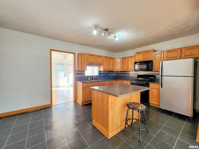 kitchen featuring tasteful backsplash, sink, a breakfast bar area, a center island, and black appliances