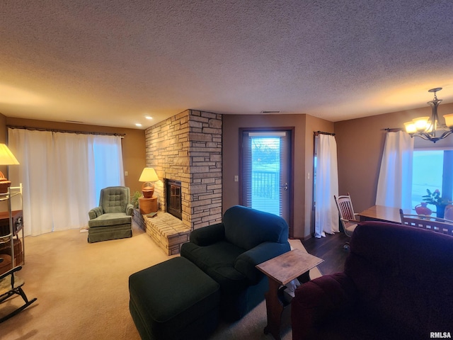 living room featuring a stone fireplace, a textured ceiling, a chandelier, and carpet