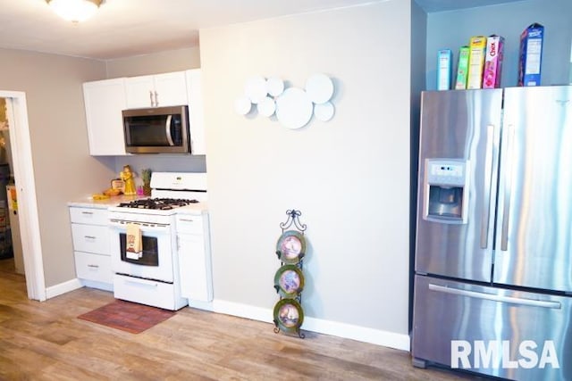 kitchen featuring stainless steel appliances, white cabinets, and light wood-type flooring