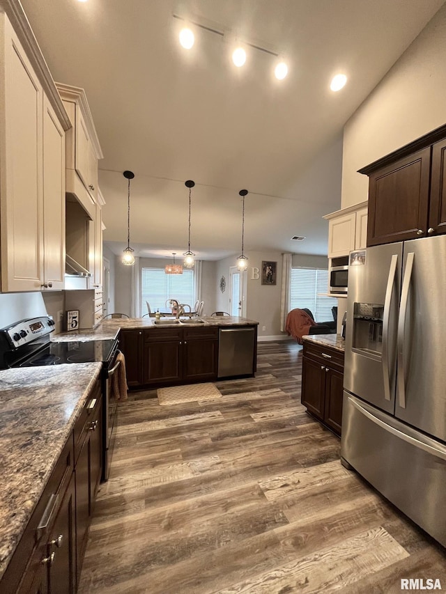 kitchen featuring appliances with stainless steel finishes, dark brown cabinets, and pendant lighting