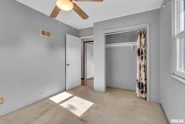 unfurnished bedroom with ceiling fan, light colored carpet, and a closet