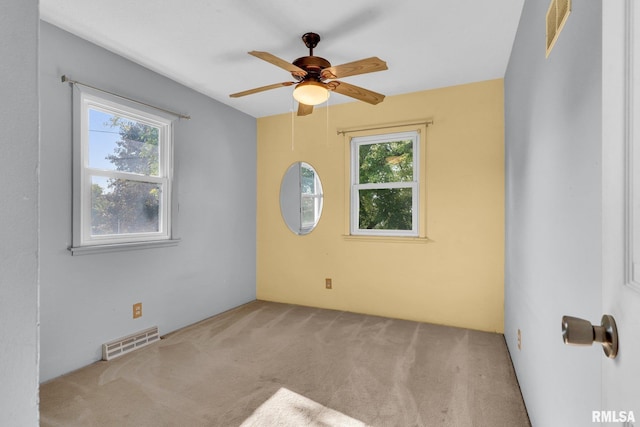 empty room featuring light carpet, ceiling fan, and a healthy amount of sunlight