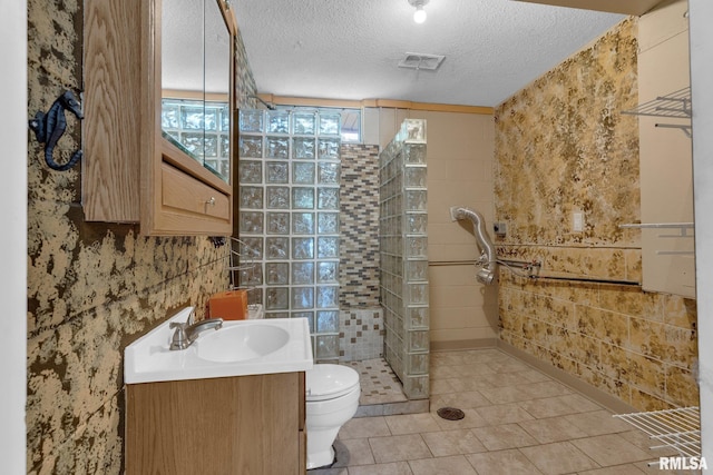 bathroom with vanity, a tile shower, a textured ceiling, and toilet