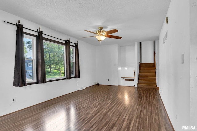 unfurnished living room featuring ceiling fan, dark hardwood / wood-style floors, and a textured ceiling