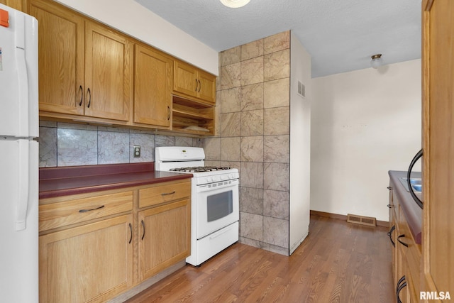 kitchen with tasteful backsplash, wood-type flooring, a textured ceiling, and white appliances