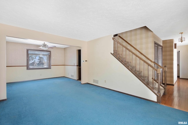 empty room with ceiling fan, carpet flooring, and a textured ceiling