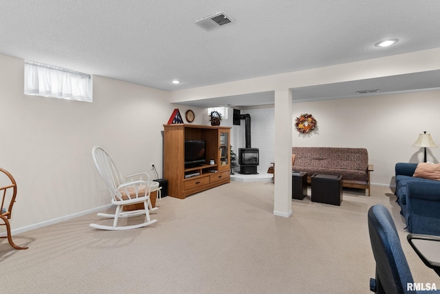 carpeted living room with a textured ceiling and a wood stove