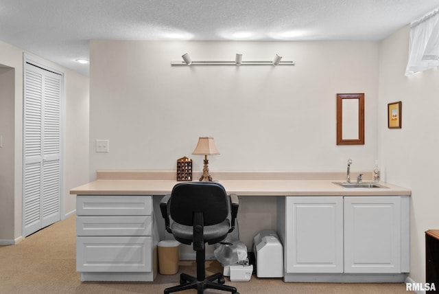 carpeted office featuring built in desk, indoor wet bar, and a textured ceiling