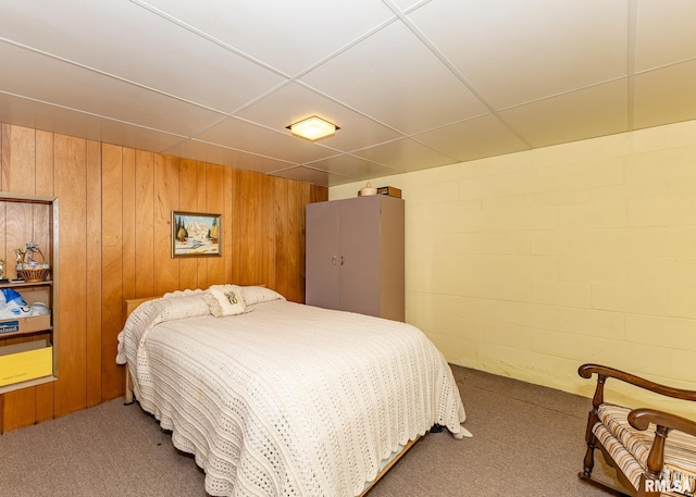 bedroom featuring carpet flooring, a paneled ceiling, and wooden walls