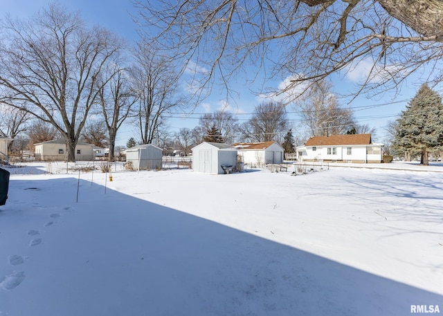 yard layered in snow featuring a storage shed