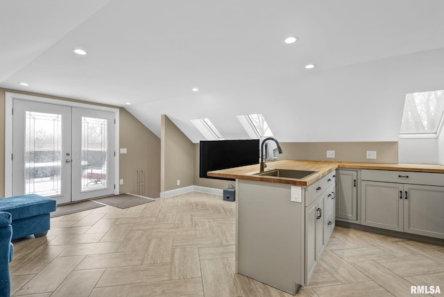 kitchen featuring butcher block countertops, sink, french doors, kitchen peninsula, and light parquet flooring