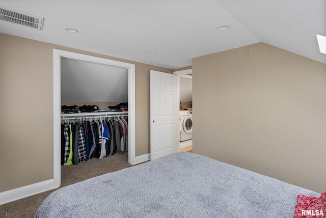 carpeted bedroom with washer / dryer, vaulted ceiling, and a closet