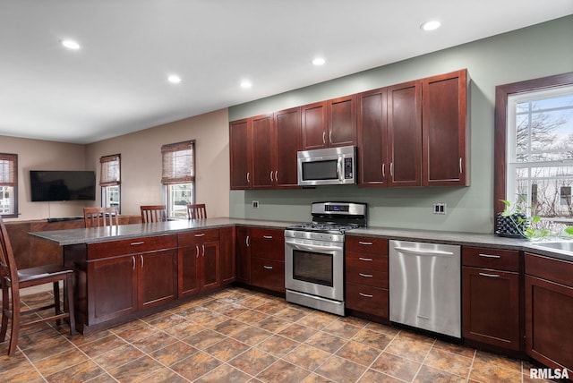 kitchen featuring stainless steel appliances, a healthy amount of sunlight, a breakfast bar, and kitchen peninsula