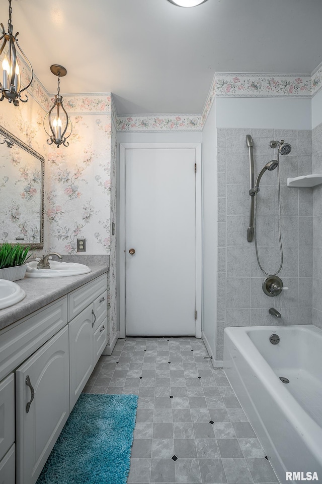 bathroom with a notable chandelier, vanity, and tiled shower / bath