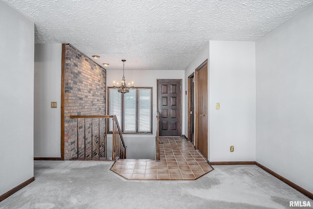 carpeted foyer entrance with a chandelier and a textured ceiling