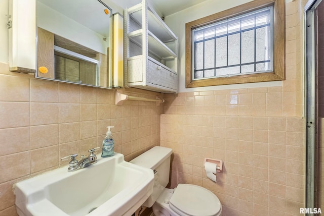 bathroom featuring sink, tile walls, and toilet