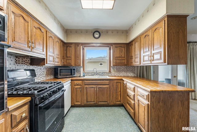 kitchen with kitchen peninsula, black gas range oven, sink, tasteful backsplash, and wood counters