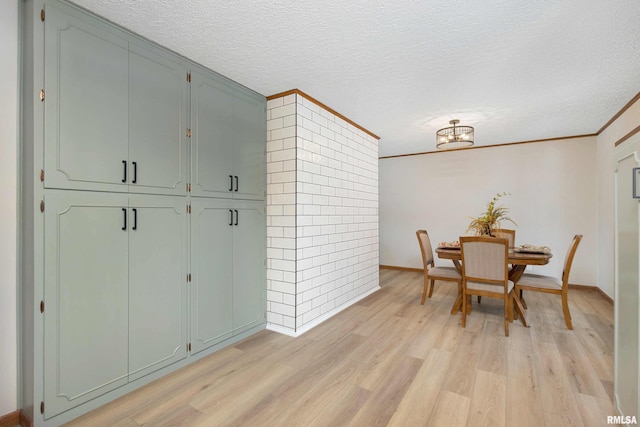 dining room with light hardwood / wood-style flooring, crown molding, and a textured ceiling