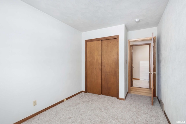 unfurnished bedroom with light carpet and a closet