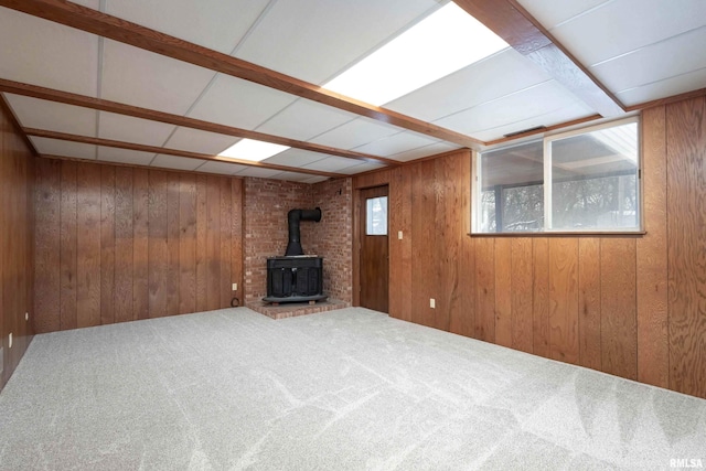 basement with a wood stove, carpet, and wooden walls