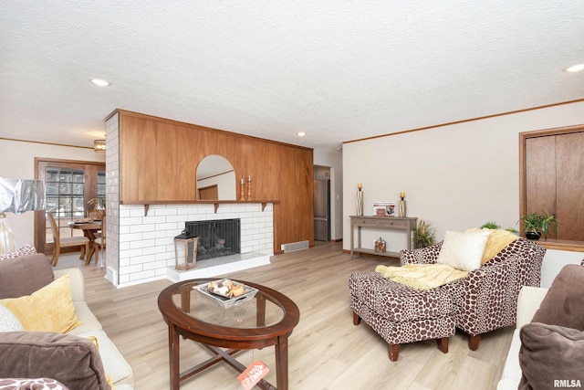 living room featuring light hardwood / wood-style flooring, crown molding, and a textured ceiling