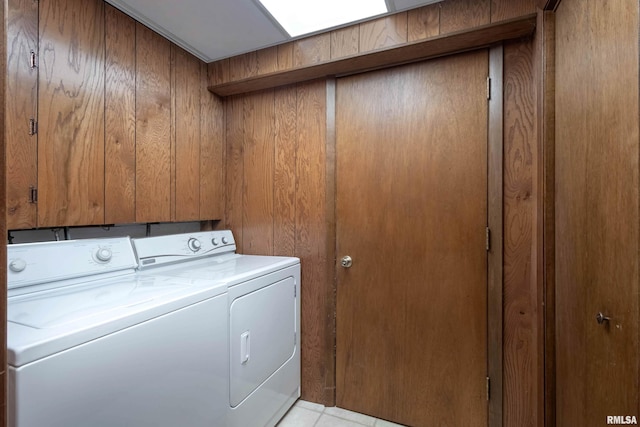 laundry area featuring wooden walls and washing machine and clothes dryer