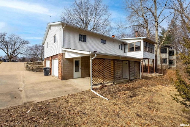 rear view of property with a garage and a sunroom