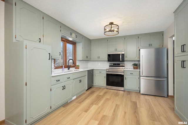 kitchen with sink, stainless steel appliances, tasteful backsplash, and light wood-type flooring