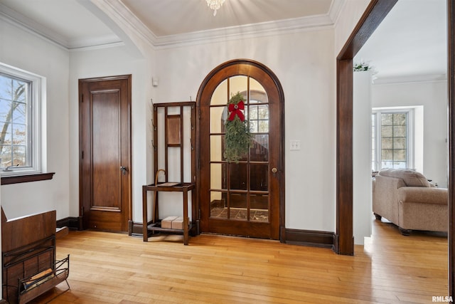 foyer featuring crown molding, a healthy amount of sunlight, and light hardwood / wood-style flooring