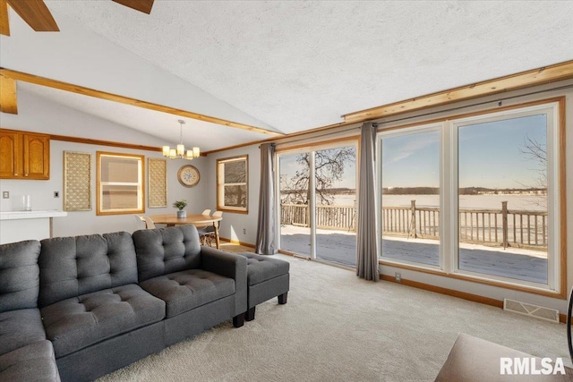 living room with a water view, a textured ceiling, lofted ceiling, a chandelier, and light carpet