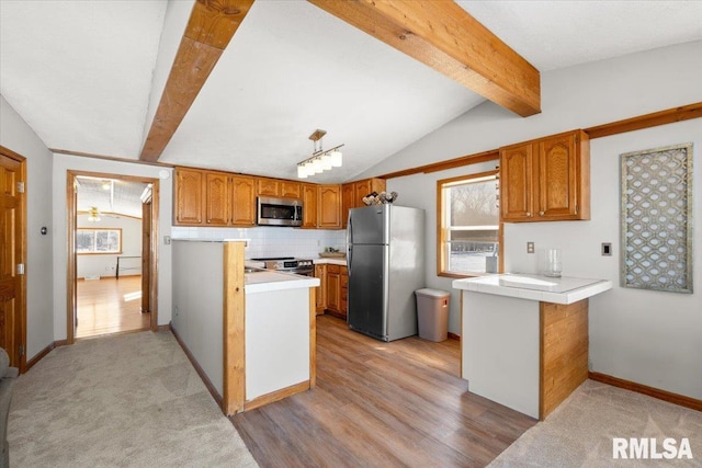 kitchen featuring kitchen peninsula, appliances with stainless steel finishes, lofted ceiling with beams, and a wealth of natural light